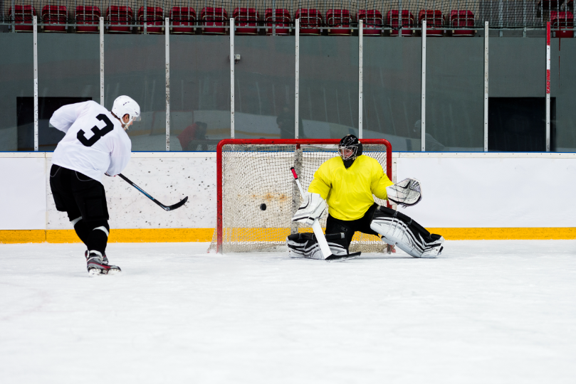 Hockey player shoots; goalie makes save.