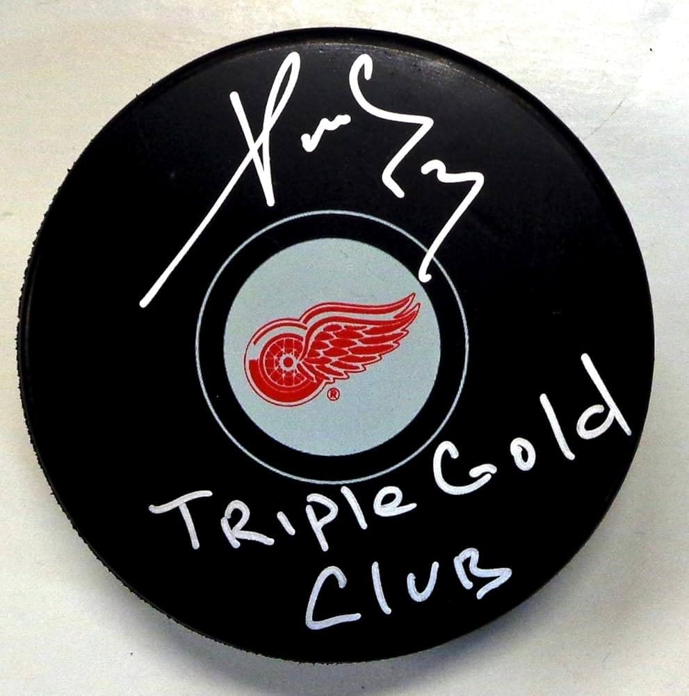 Hockey puck signed with "Triple Gold Club" and a signature, featuring the Detroit Red Wings logo.