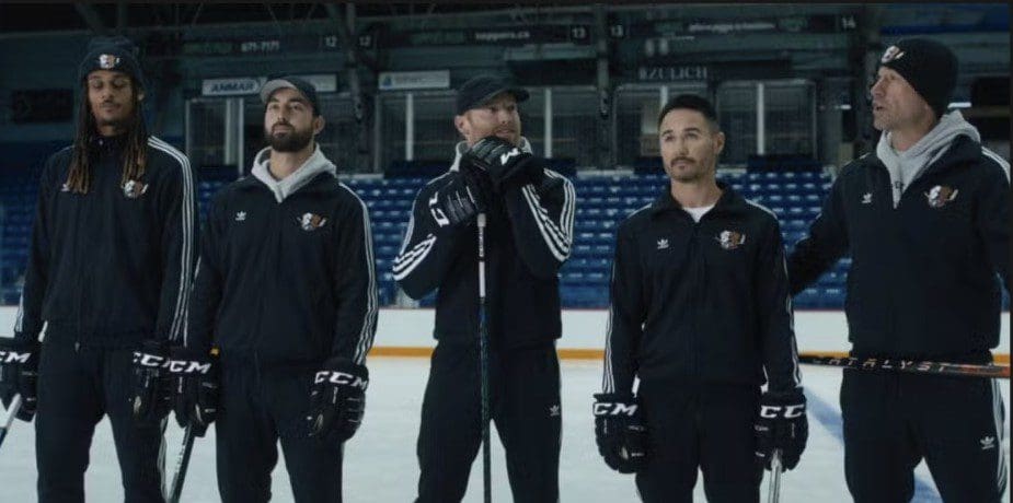 Three hockey players standing on the ice rink, wearing black uniforms.
