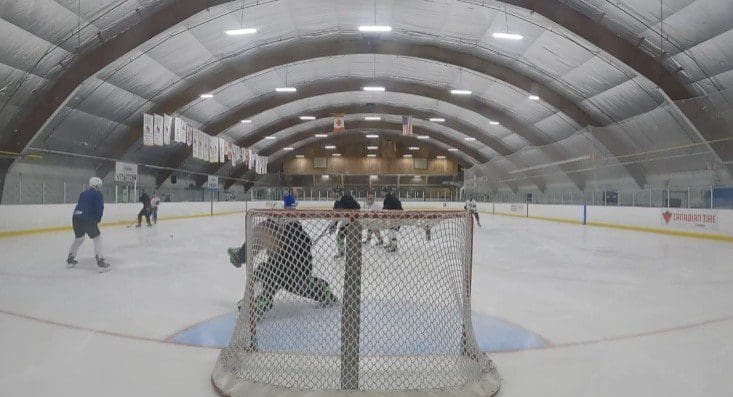 Ice hockey game action near the goal with goalie and players.