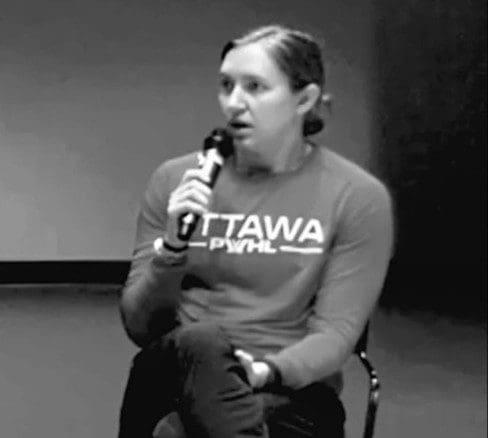 Person speaking into a microphone during an event.