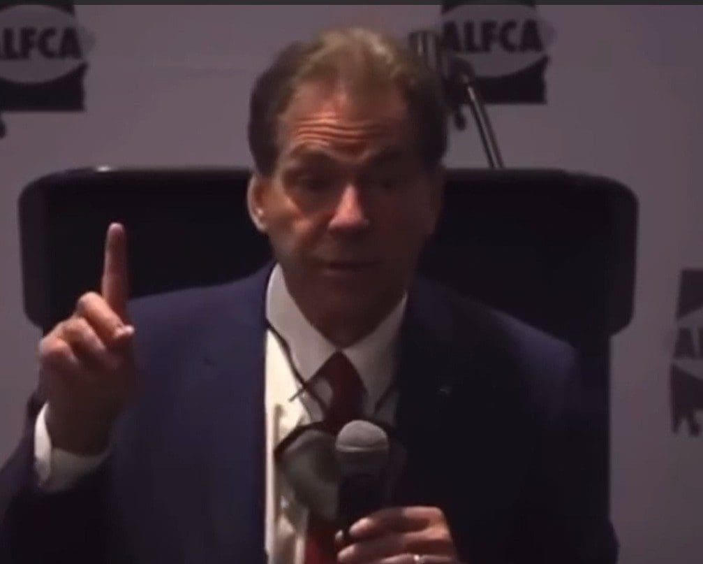 Man in suit speaking into microphone at event.