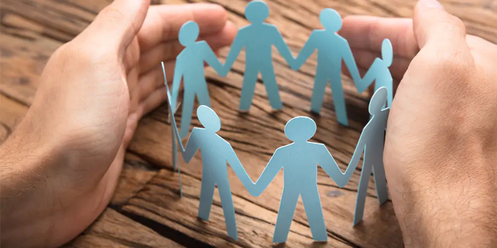 Paper figures holding hands in a circle symbolizing unity.