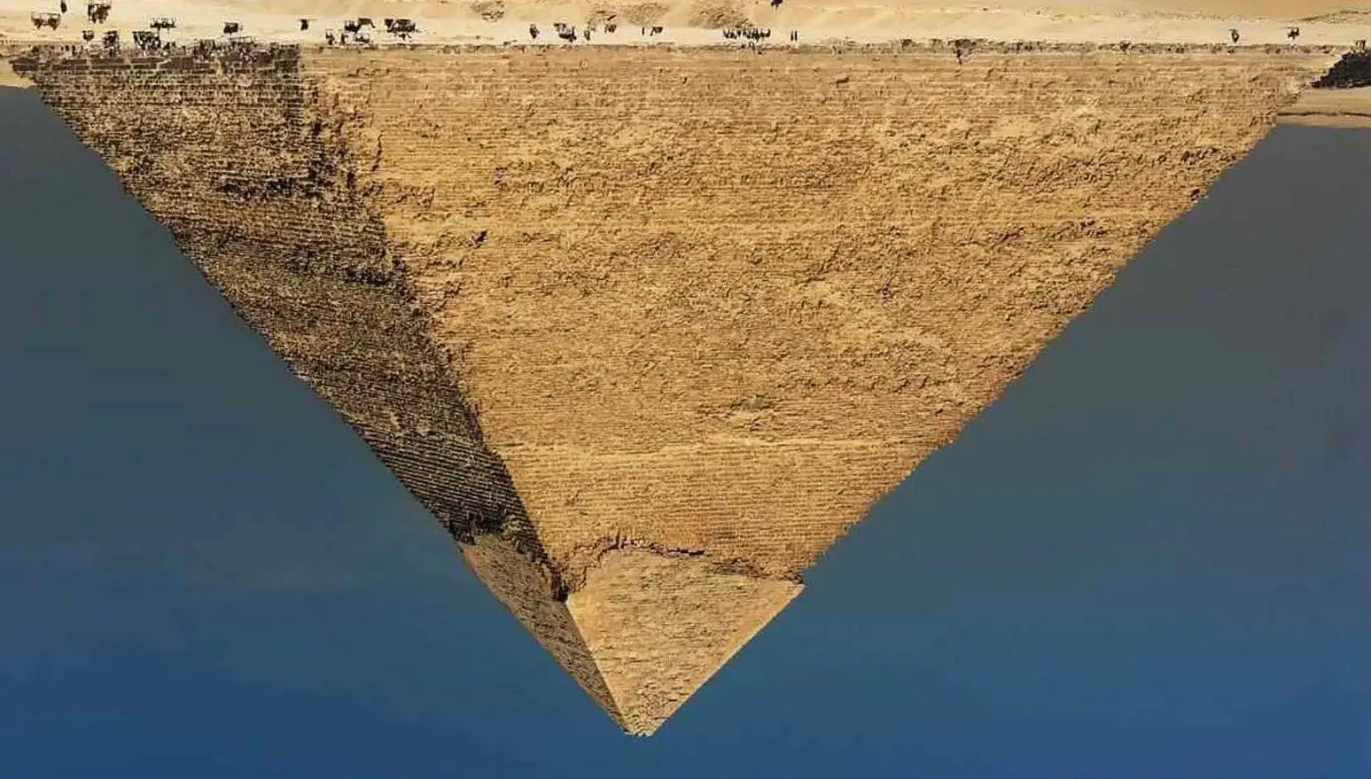 Aerial view of a pyramid in a desert with a clear blue sky.