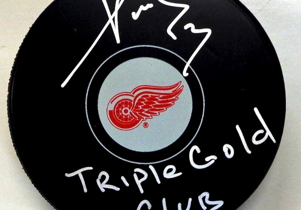 Hockey puck signed with "Triple Gold Club" and a signature, featuring the Detroit Red Wings logo.