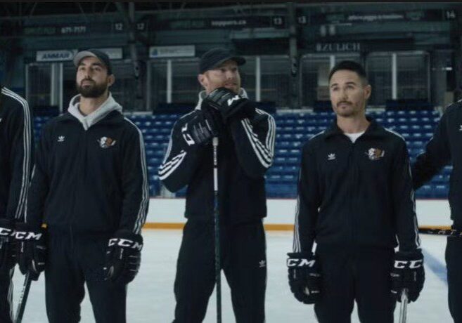 Three hockey players standing on the ice rink, wearing black uniforms.