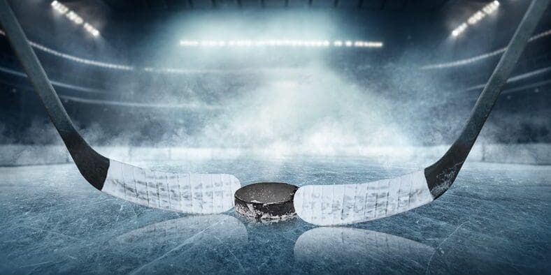 A hockey puck on ice in a foggy rink under bright lights.