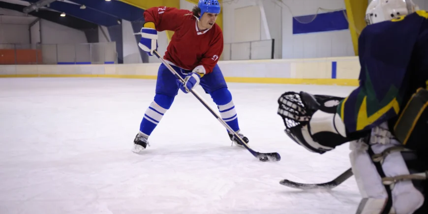 Ice hockey player shoots puck at goalie.
