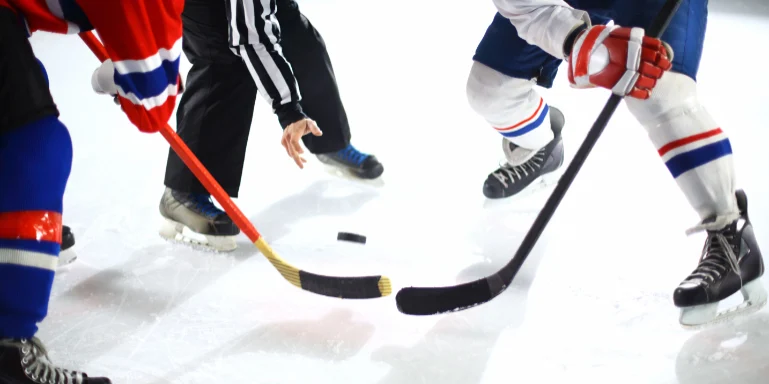 Ice hockey players face-off on rink.