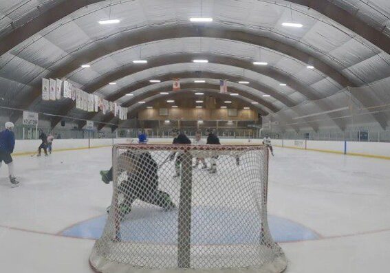 Ice hockey game action near the goal with goalie and players.