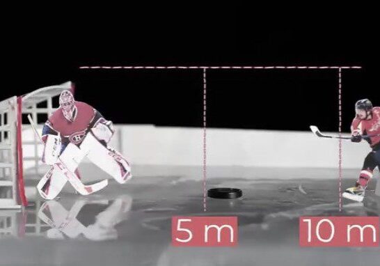 Hockey goalie diving to stop a puck on an ice rink.