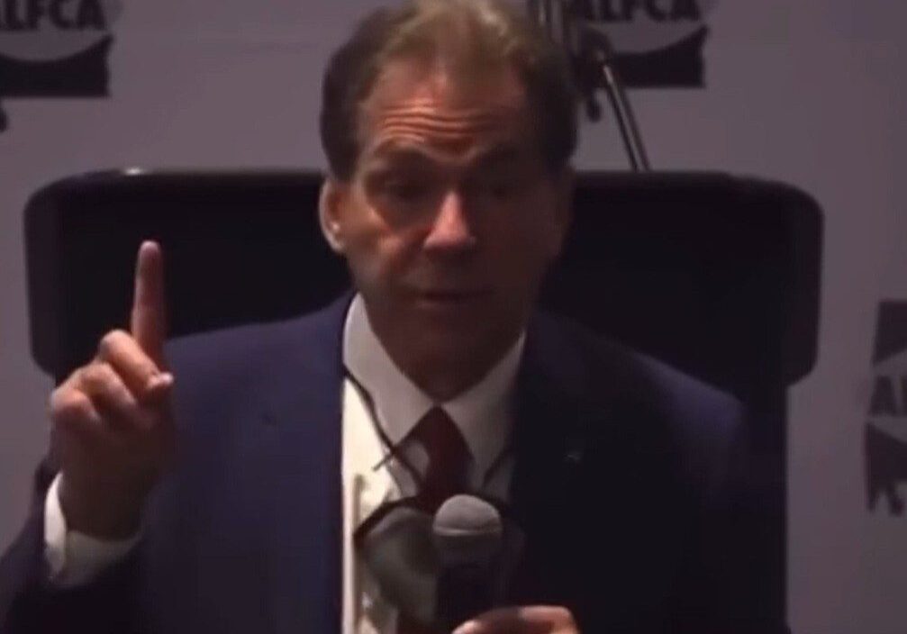 Man in suit speaking into microphone at event.