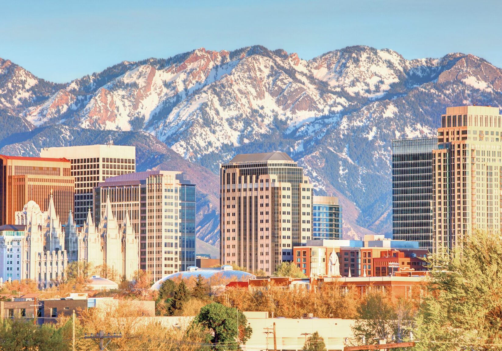 City skyline with mountains in the background during daytime.