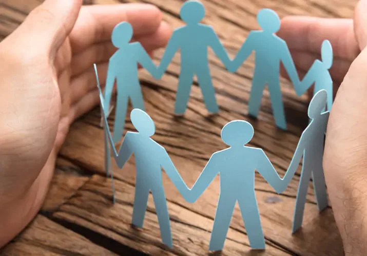 Paper figures holding hands in a circle symbolizing unity.