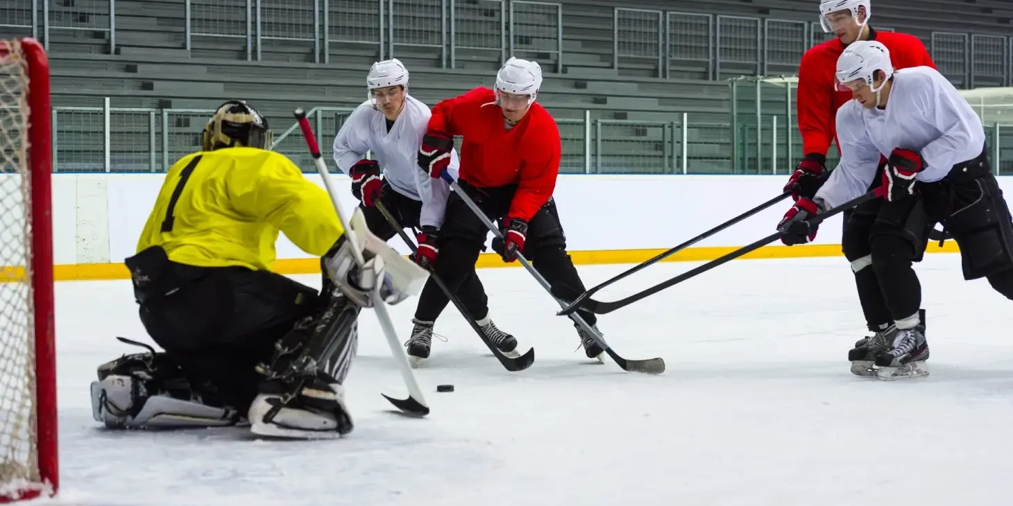 Hockey goalie defends against three players.